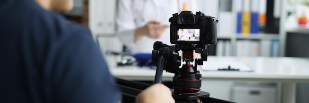 Fotografo che riprende il medico sulla fotocamera utilizzando il treppiede e il cursore del primo piano