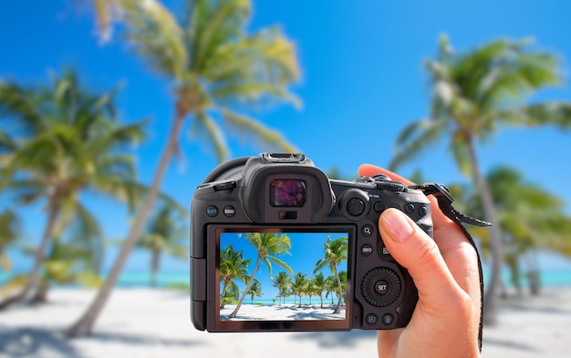 Fotografo che tiene in mano una fotocamera digitale e scatta una foto del paesaggio della spiaggia tropicale
