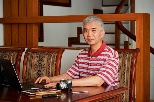 Fotografo cinese che lavora al computer portatile