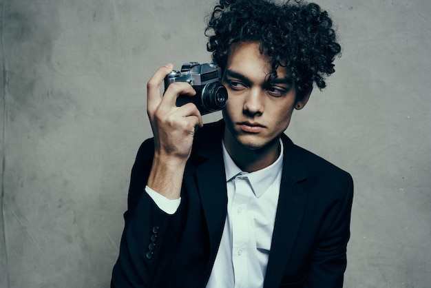 Fotografo con fotocamera all'interno su sfondo grigio e giacca riccioli camicia modello foto di alta qualità