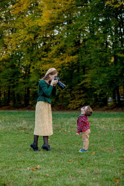 Fotografo della donna che fotografa il bambino da spendere fuori nel parco