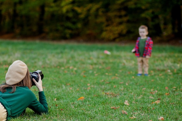 Fotografo della donna che fotografa il bambino da spendere fuori nel parco