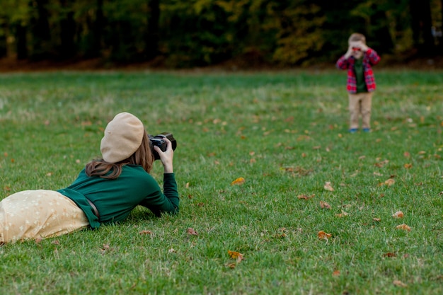 Fotografo della donna che fotografa il bambino da spendere fuori nel parco