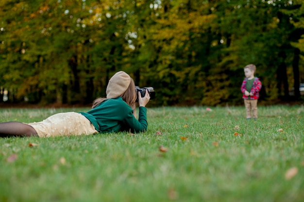 Fotografo della donna che fotografa il bambino da spendere fuori nel parco