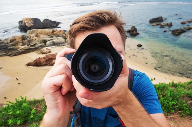 Fotografo di giovane uomo caucasico con macchina fotografica durante le vacanze estive e i viaggi di vacanza