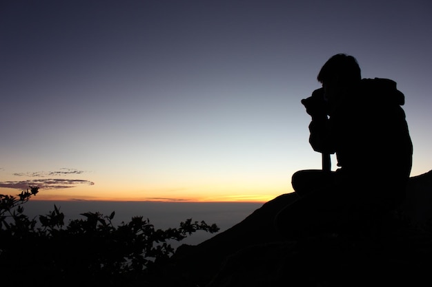 Fotografo di sagoma in cima al monte