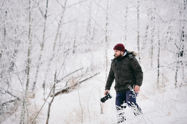 Fotografo di viaggiatori che scatta foto nella foresta invernale