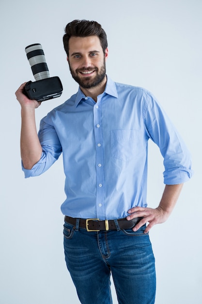 Fotografo felice che tiene una macchina fotografica nello studio