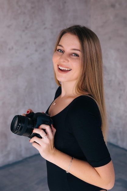 Fotografo femminile allegro che sorride e che posa con la macchina fotografica