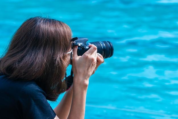 Fotografo femminile che cattura maschera con la sua macchina fotografica di DSLR ad una piscina