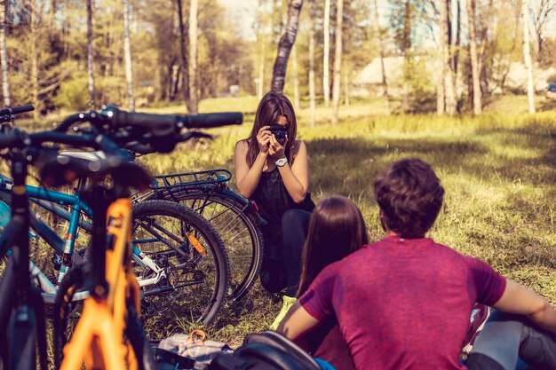 Fotografo femminile che spara alle coppie sportive dopo la guida in bicicletta nella foresta estiva.