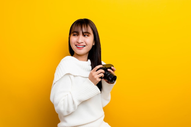 Fotografo femminile con la macchina fotografica le giovani donne amano scattare foto Amante della fotocamera scattare foto nello studio giallo