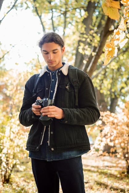 Fotografo maschio che controlla le immagini sulla fotocamera nella foresta autunnale