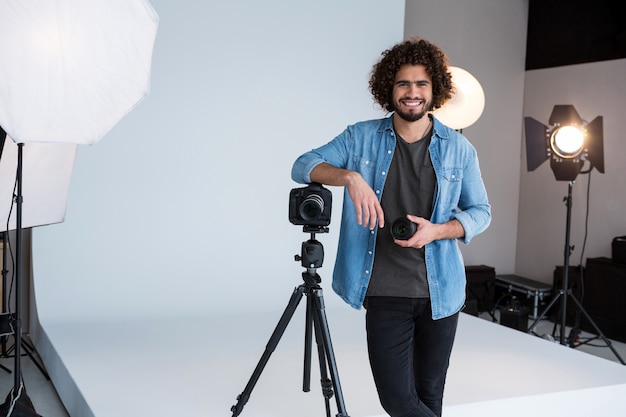 Fotografo maschio felice che sta nello studio