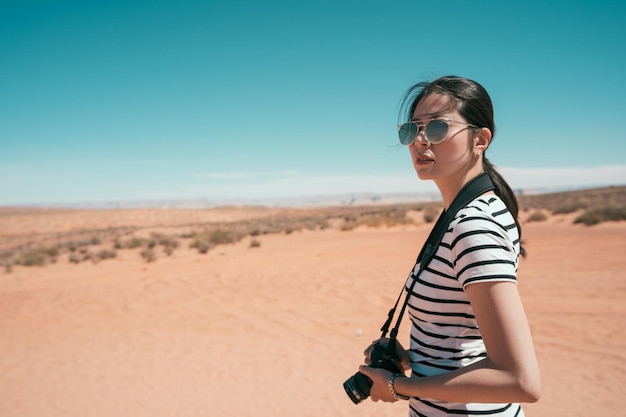 Fotografo naturalistico che scatta foto all'aperto durante un'escursione nel parco nazionale del Grand Canyon. la giovane signora viaggia da sola verso la montagna di sabbia negli Stati Uniti. femmina con occhiali da sole in piedi in una giornata di sole nel deserto