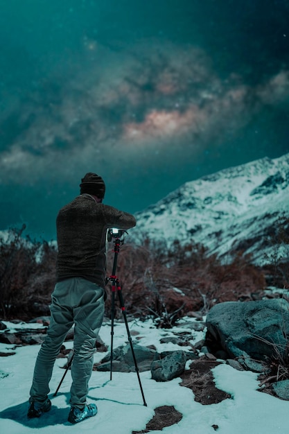 Fotografo nella neve di notte per scattare foto delle stelle e della Via Lattea sulla montagna innevata