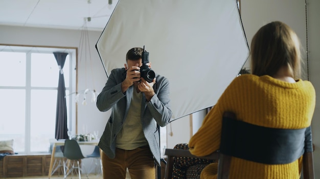 Fotografo professionista che scatta foto di modelle con una fotocamera digitale lavorando in uno studio fotografico