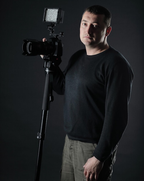 Fotografo professionista con una telecamera isolata su sfondo nero