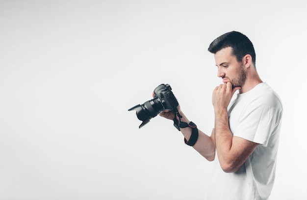 Fotografo professionista guarda lo schermo e il pensiero. Dopo aver scattato la foto utilizzando attrezzature fotografiche professionali. Thouhtful uomo calmo e pacifico. Vista laterale.