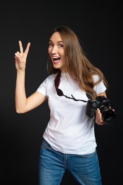 Fotografo ragazza con una macchina fotografica sorridente su uno sfondo nero