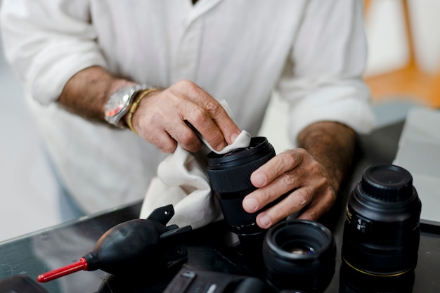 Fotografo senior che pulisce il suo obiettivo