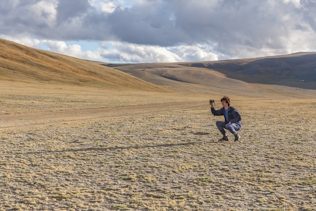 Fotografo turistico che cattura maschera delle colline con le montagne in Altai mongolo