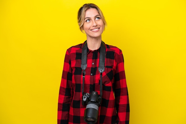 Fotografo uruguaiano donna isolata su sfondo giallo alzando lo sguardo sorridendo