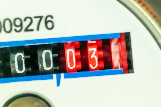 Fragment of the front panel of mechanical water counter numbers on red and black field close up Concept of communal payments and consumption of water