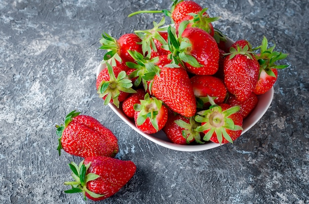 Fragola appetitosa nella ciotola su una priorità bassa grigia.