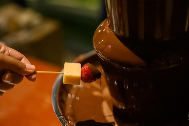 Fragola che si tuffa nella fonduta di cioccolato, primo piano