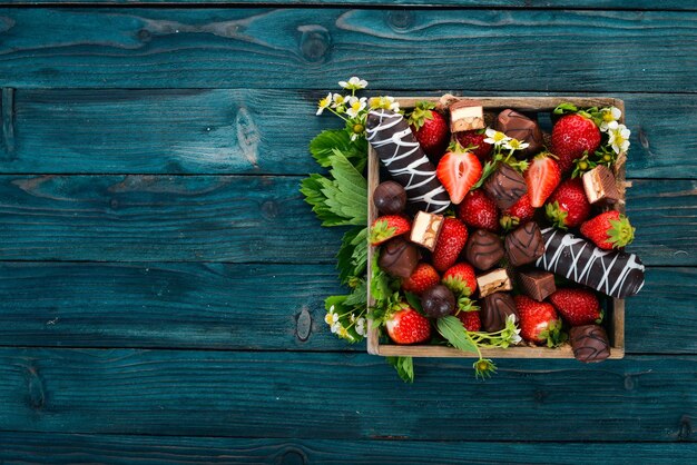 Fragola con cioccolato in una scatola di legno. Su uno sfondo di legno. Vista dall'alto. Copia spazio.