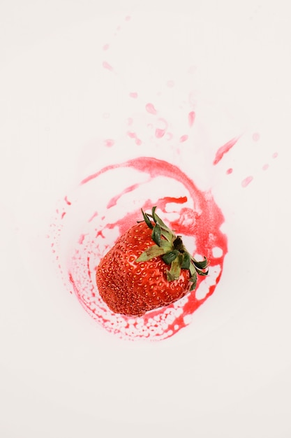 Fragola e gocce di acqua fresche rosse su bianco