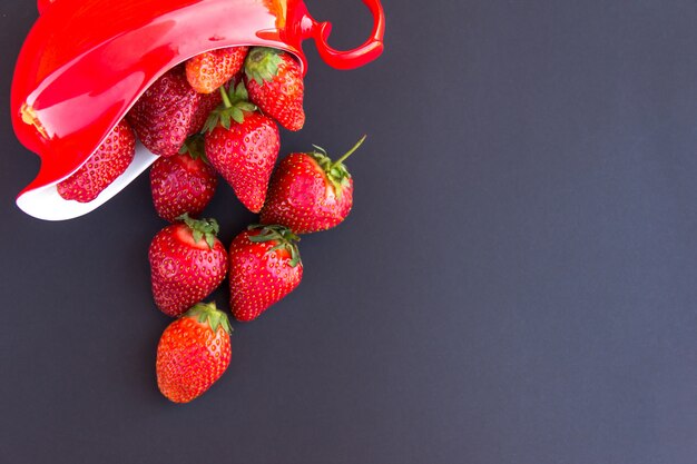 Fragola fresca rossa in brocca rossa sul nero