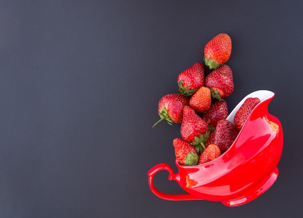 Fragola fresca rossa in brocca rossa sul nero