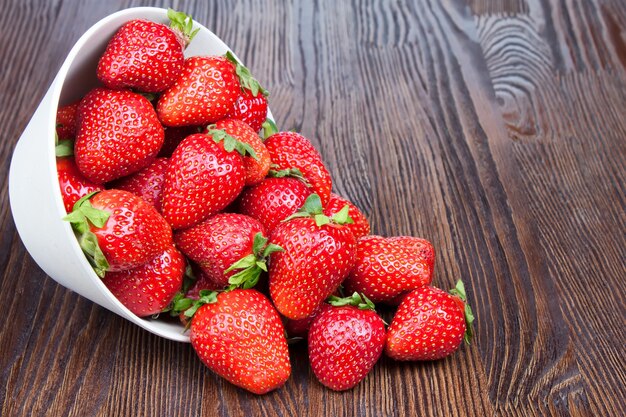 Fragola fresca rossa in una ciotola su fondo di legno marrone