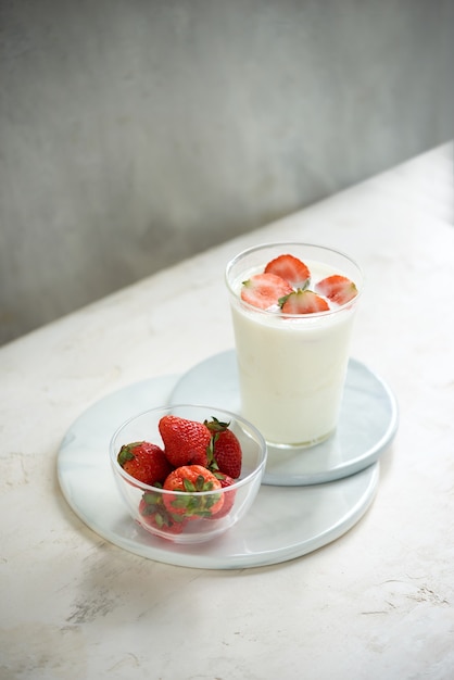 Fragola fresca su un bicchiere con yogurt da dessert e fragola su sfondo bianco