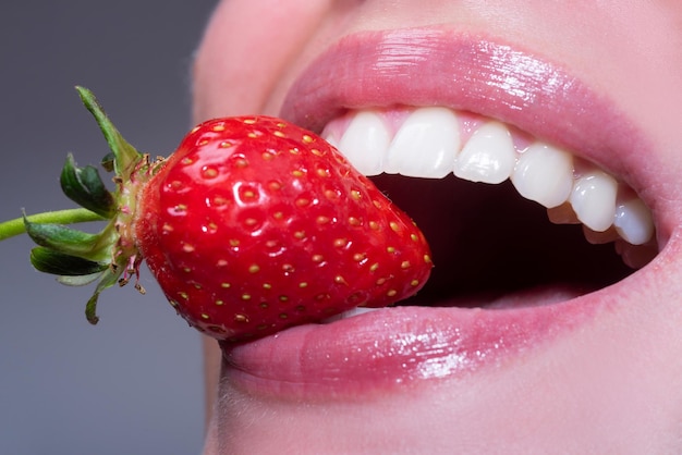 Fragola in labbra Fragola rossa in bocca donna vicino Primo piano del sorriso con denti bianchi e sani