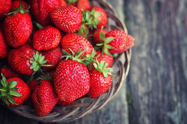 Fragola in piatto di vimini su fondo di legno