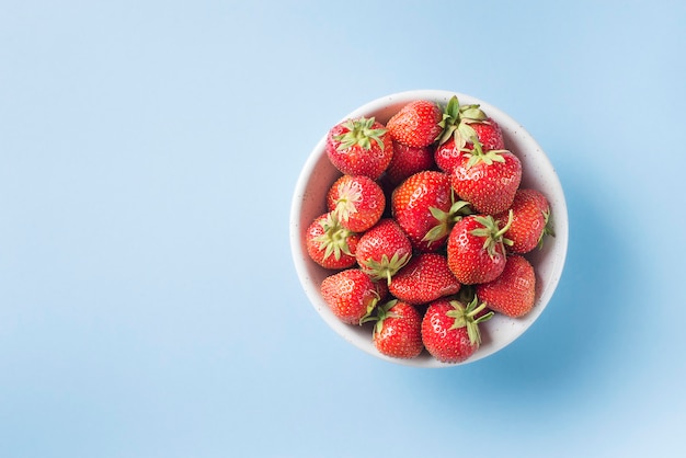 Fragola matura nella vista superiore della ciotola sull'azzurro