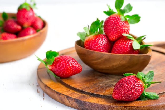 Fragola matura sullo sfondo ciotola di frutti di bosco, fuoco selettivo