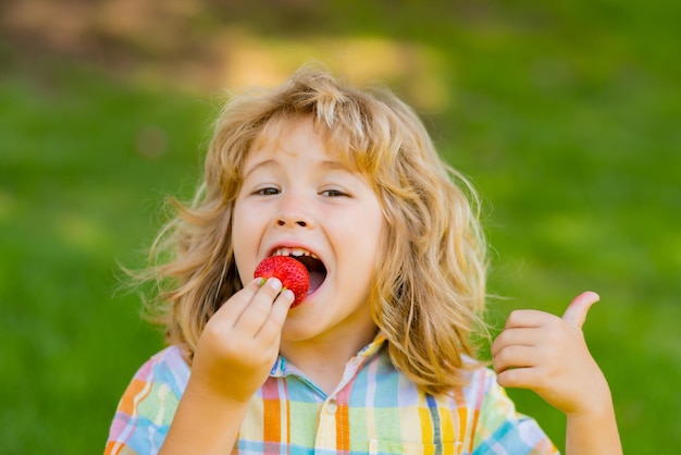 Fragola per bambini bambino felice che mangia fragola fresca succosa dolce matura bambino che tiene fragole co