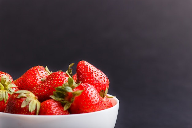 Fragola rossa fresca in ciotola bianca su fondo nero