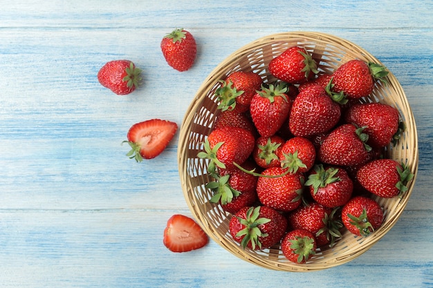 Fragola rossa in un cesto di vimini su un tavolo di legno azzurro.