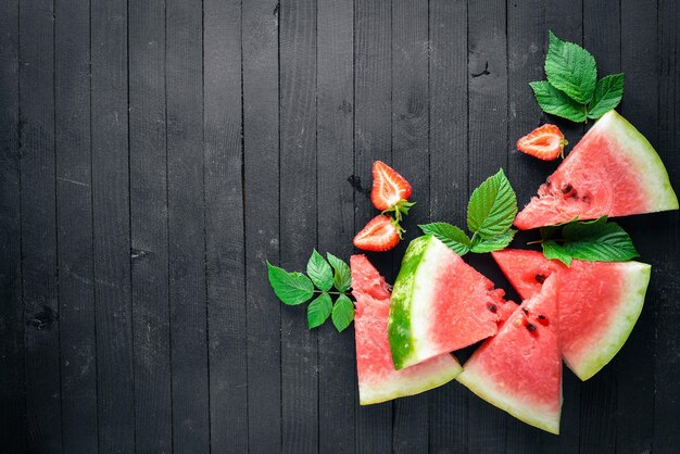 Fragole anguria menta Su una tavola di legno Affettatura di frutta Vista dall'alto Spazio libero per il testo