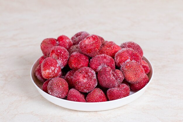 Fragole congelate in un piatto bianco sul tavolo della cucina