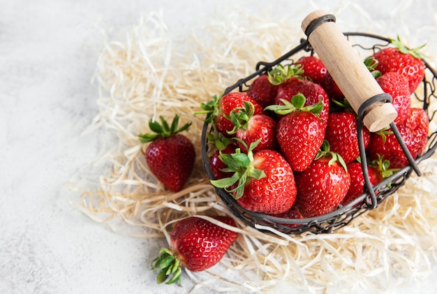 Fragole deliziose mature fresche in un cesto su uno sfondo di pietra grigia