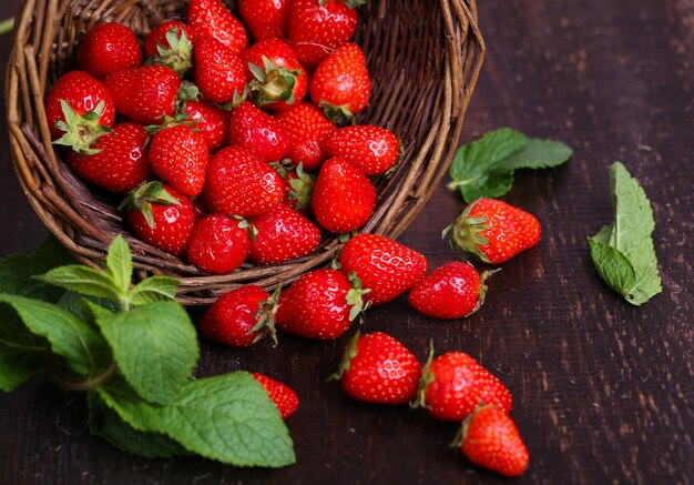 Fragole dolci mature in cestino di vimini su fondo di legno