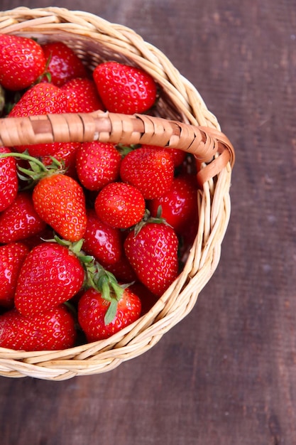 Fragole dolci mature in cestino di vimini su fondo di legno