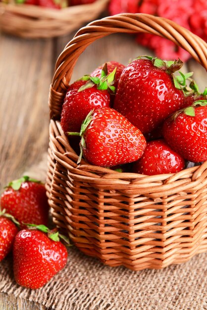 Fragole dolci mature in cestino di vimini sul primo piano della tavola