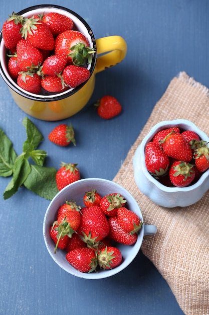 Fragole dolci mature in tazza su fondo di legno di colore